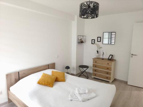 a bedroom with a large white bed with yellow pillows at STELLA Modern apartment, terrace and sea view Donville in Donville-les-Bains