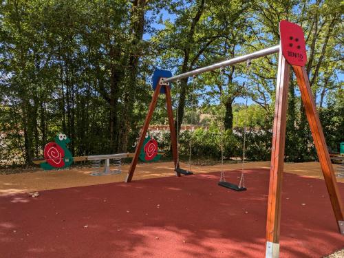 a swing set in a park with trees at Hob La Truffière in Gignac