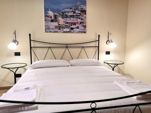 a bedroom with a large white bed with two tables at Il Borgo Ospitale - Albergo Diffuso in Rotonda