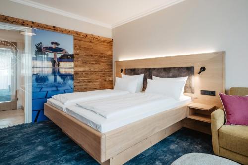 a bedroom with a large bed and a chair at Appartementhaus Absmeier in Bad Füssing