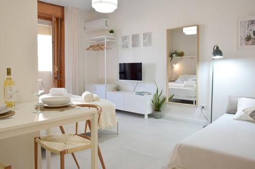 Quartu Sant'ElenaにあるPoetto Studio, Private Parking, SmartTV, Park Viewの白いリビングルーム(ベッド1台、ダイニングテーブル付)