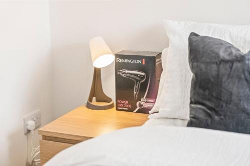 a bed with a book and a lamp on a night stand at Modern 4-Bed, Parking, Pool Table, Sleeps 11 in Bescot