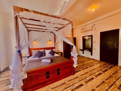 a bedroom with a canopy bed and a wooden floor at Villa Green View in Hikkaduwa