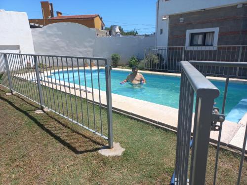 a man in a swimming pool behind a fence at Mar Loft Monoambiente in Miramar