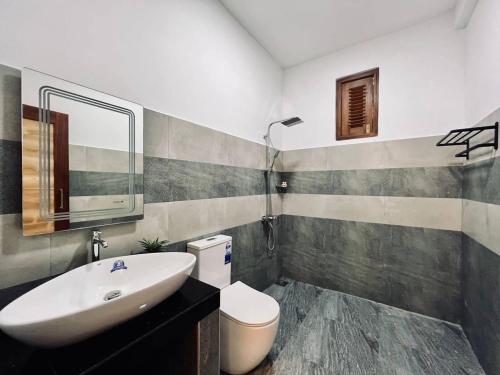a bathroom with a sink and a toilet and a mirror at Villa Green View in Hikkaduwa