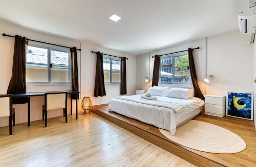 a bedroom with a bed and a desk and windows at Cat House BKK in Bangkok
