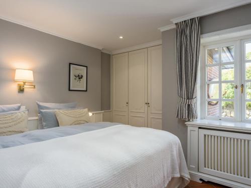Un dormitorio con una cama blanca y una ventana. en Beach Bungalow Sylt 2, en Dikjendeel