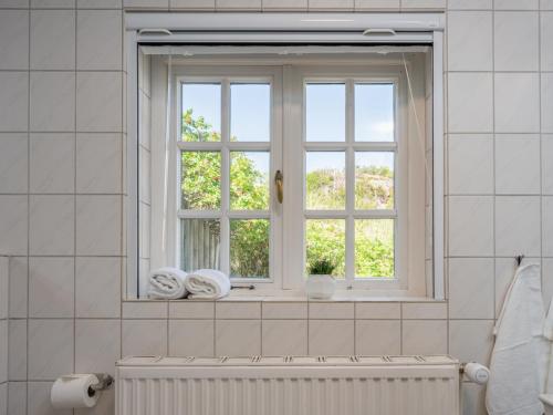 Un baño con una ventana con toallas en un radiador. en Beach Bungalow Sylt 1, en Dikjendeel