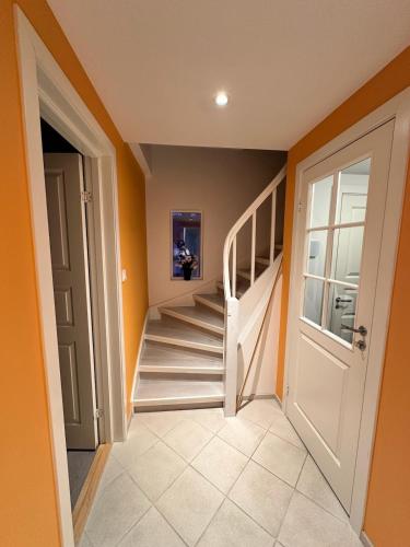 a hallway with orange walls and a white staircase at Cozy house with a sea view in Knarrvika