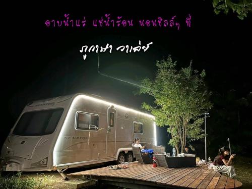 a man sitting on a table next to a trailer at Phukasa Valley Maesot in Ban Mae Kasa