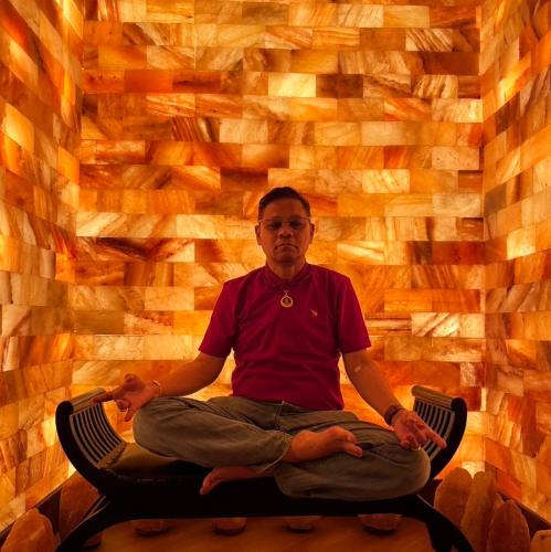 a man sitting in a chair in a room with a wall at Phukasa Valley Maesot in Ban Mae Kasa
