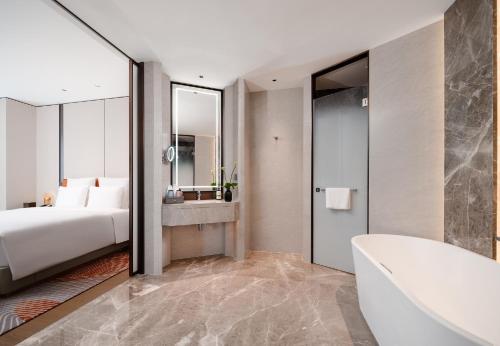 a bedroom with a bed and a tub and a sink at Pullman Chongqing Xiyue in Chongqing
