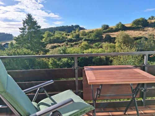 a table and chairs on a balcony with a view at Ferienhaus Eifelhöhe mit Maarpanorama in Schalkenmehren