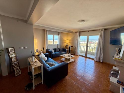 a living room with a blue couch and a large window at Home in Paradise Costa de Lavos in Costa de Lavos