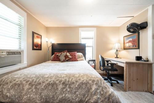 een slaapkamer met een bed, een bureau en een computer bij Downtown Oasis - Steps to Dining, Cafes & Bars in Colorado Springs