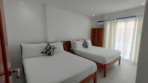 a bedroom with two beds and a window at Ola De Baler Hotel in Baler