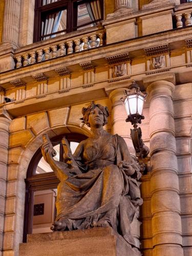 a statue of a woman sitting in front of a building at Alchymist Prague Castle Suites Hotel in Prague