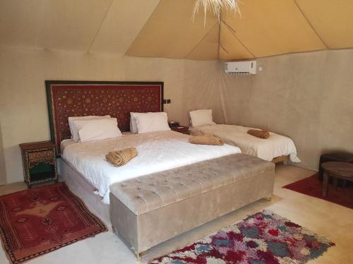 a bedroom with two beds and a ottoman at Merzouga Desert Experience Camp-Erg Chebbi Sunset & Camel Ride in Merzouga