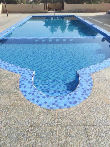 a swimming pool with blue tiles on the ground at Merzouga Desert Experience Camp-Erg Chebbi Sunset & Camel Ride in Merzouga