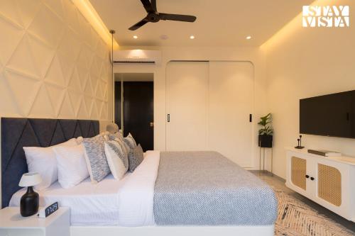 a bedroom with a bed and a flat screen tv at StayVista at The Amaryllis with Heated Pool & Projector Set-Up in Karjat