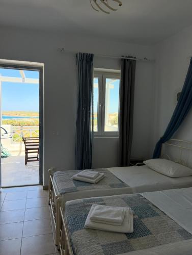 two beds in a bedroom with a view of a patio at Antiparos Diamond in Antiparos