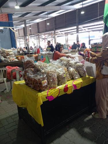 a woman standing at a table in a market at Lu&Lu Rooms & Homestay in Dungun