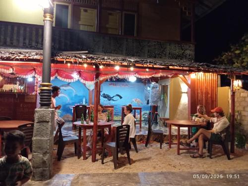 a group of people sitting at tables in front of a restaurant at Three Ken Homestay & Cafe in Manado