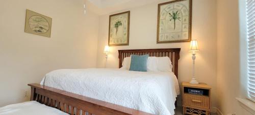 a bedroom with a bed and two pictures on the wall at Beach & Palms condo condo in South Padre Island