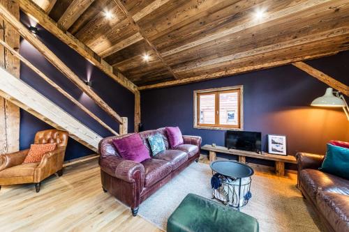 a living room with leather furniture and a wooden ceiling at Chalet Saint De l'Elephant in Saint-Jean-dʼAulps