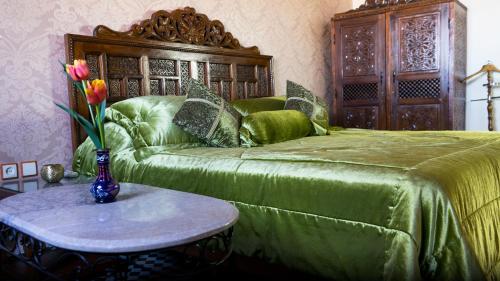 a bedroom with a bed and a vase of flowers on a table at Riad Dar El Ouedghiri in Fès