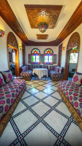 a living room with couches and a table and stained glass windows at Riad Dar El Ouedghiri in Fès