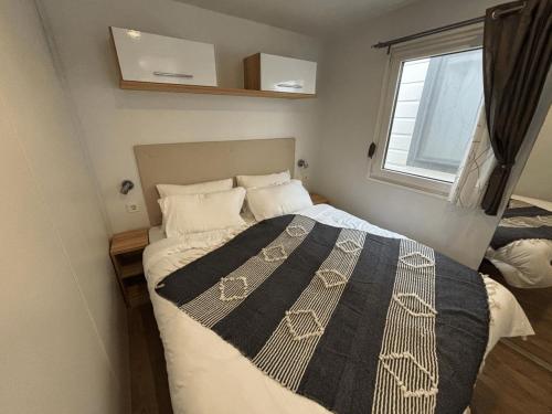 a bedroom with a bed with a black and white blanket at Estivo mobile homes on Camping Bella Italia in Peschiera del Garda