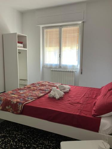 een slaapkamer met een groot bed met rode lakens en een raam bij La melanetta in Noli