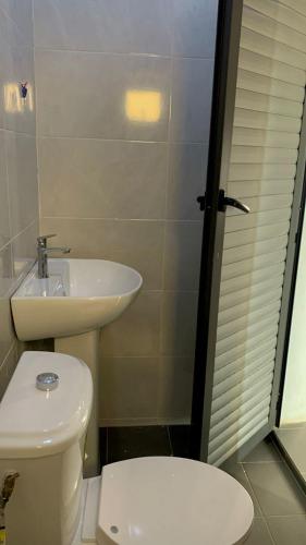 Un baño con un inodoro blanco y un lavabo. en Maison d'hôtes Jaxaay, en Keur Massar