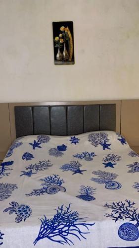 Una cama con un edredón azul y blanco. en Maison d'hôtes Jaxaay, en Keur Massar