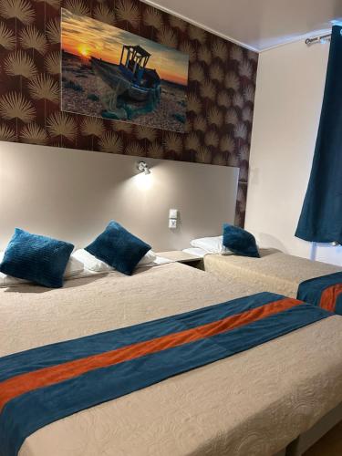 two beds with blue pillows in a hotel room at Hotel de Normandie in Gournay-en-Bray