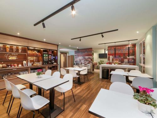 a restaurant with white tables and white chairs at B&B Hotel Berlin-Dreilinden in Kleinmachnow