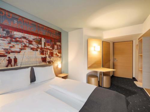 a bedroom with a white bed and a painting on the wall at B&B Hotel Berlin-Dreilinden in Kleinmachnow