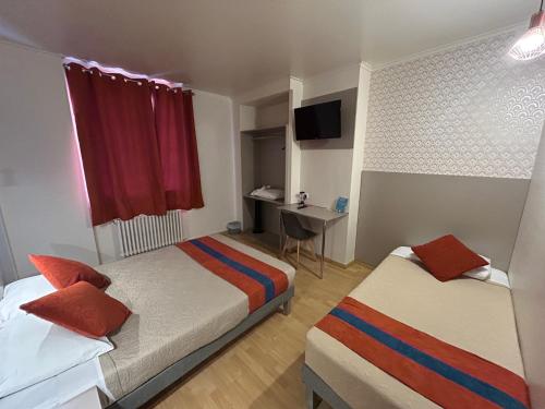 a hotel room with two beds and a desk at Hotel de Normandie in Gournay-en-Bray