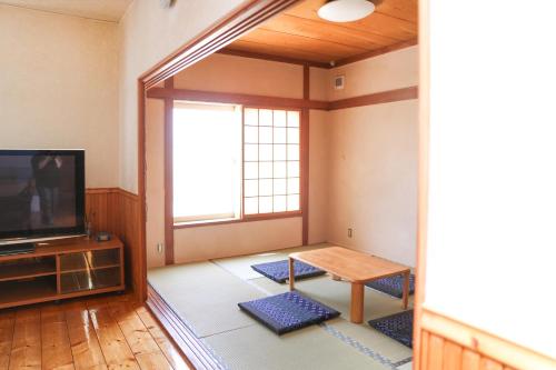a living room with a tv and a table in it at Flower House Toya in Lake Toya