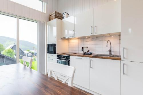 a kitchen with white cabinets and a large window at Åre Travel - Villa Solbringen eller Lilla Sol in Åre