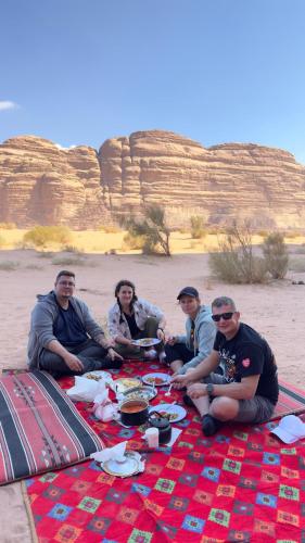 a group of people sitting on a picnic blanket at Wadi Rum Star Camp in Wadi Rum