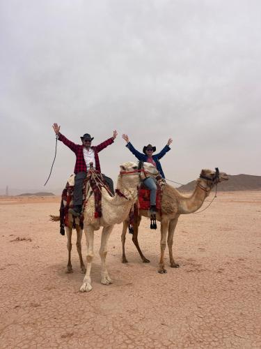 two people are riding on camels in the desert at Wadi Rum Star Camp in Wadi Rum