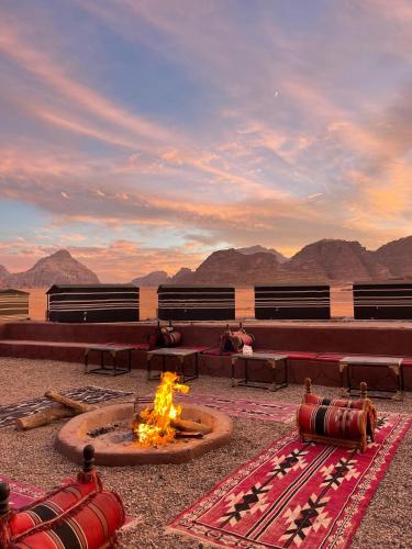 a room with a fire pit with mountains in the background at Wadi Rum Star Camp in Wadi Rum