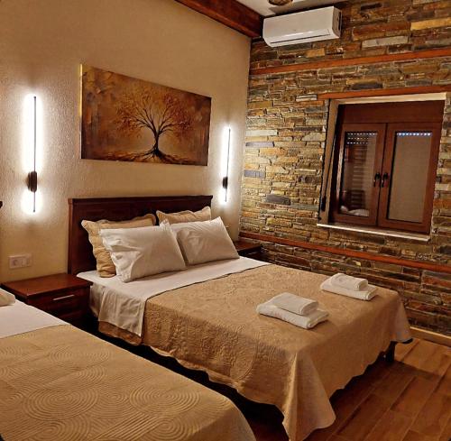 a bedroom with two beds and a brick wall at Petroula Suites Pozar in Kato Loutraki