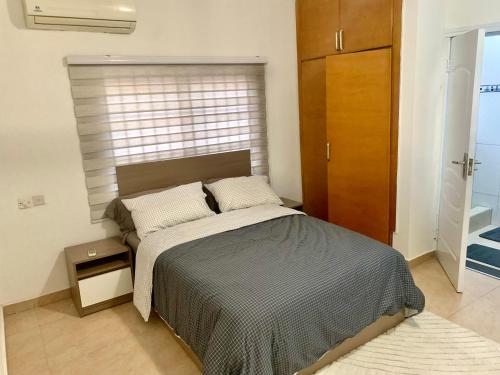 a bedroom with a bed and a wooden cabinet at Cozy comfortable One bedroom close to Airport in Accra