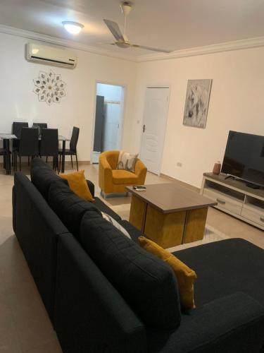a living room with a black couch and a tv at Cozy comfortable One bedroom close to Airport in Accra