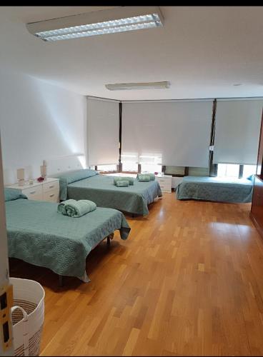 una camera con tre letti e un pavimento in legno di Habitación para descansar en pleno centro ad Alicante