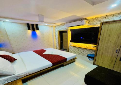 a bedroom with a bed and a flat screen tv at Hotel Manish International in Kashi