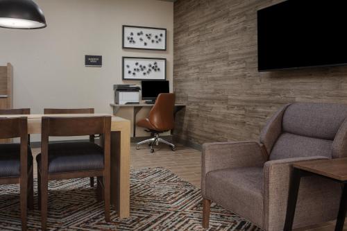 a waiting room with a table and chairs and a tv at Candlewood Suites St. Robert by IHG in Saint Robert